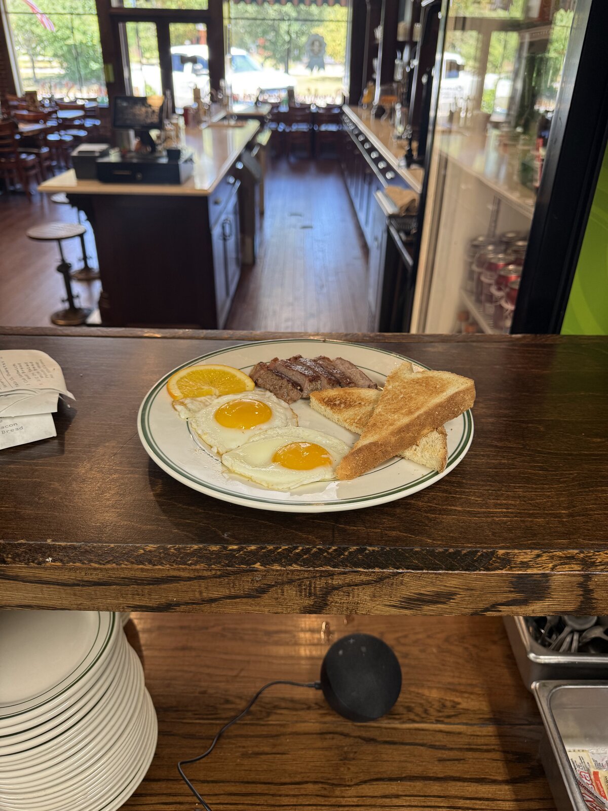 Steak and eggs plate with toast and orange slice on the counter