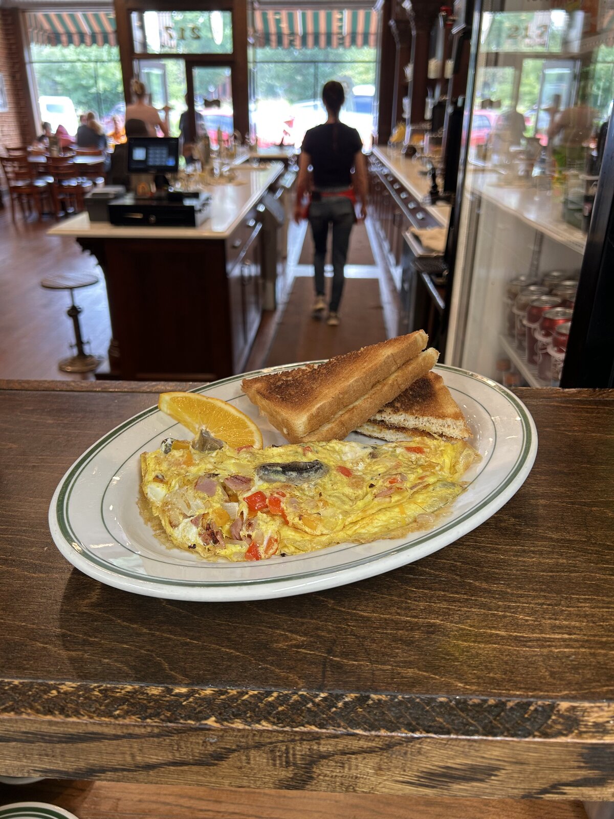 Three-egg omelet with toast and an orange slice on the counter